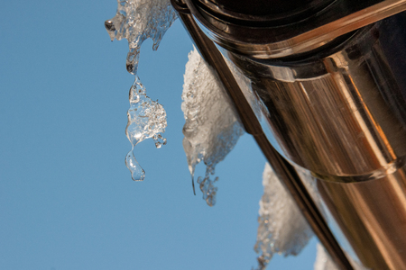 icicles dripping from the roof of the house on a background of blue skyの写真素材