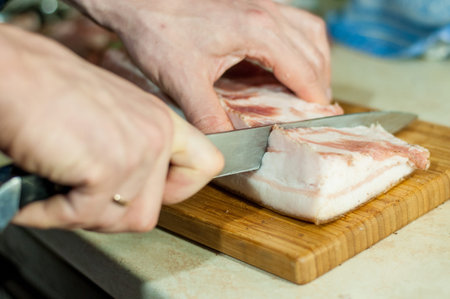 man cuts the raw lard for saltingの写真素材