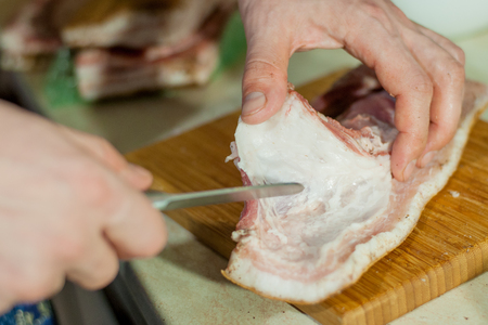 man cuts the raw lard for saltingの写真素材