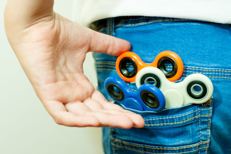 The boy pulls the spinner out of his pocket