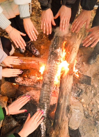 Men's hands, women's, children's hands against a bonfire