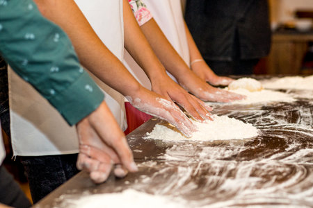 Close-up of female hands kneading dough in the kitchenの写真素材