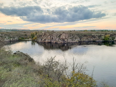 Beautiful autumn landscape with river and clouds in the sky at sunsetの写真素材