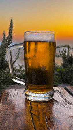 Mug of beer on a wooden table against the background of the seaの写真素材