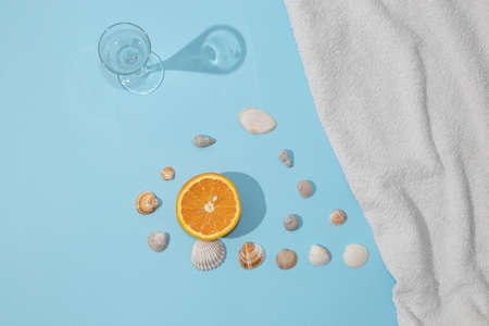 Summer scene with bright blue beach towel and glass and orange fruit and shell. Cold drink or refresment concept.の写真素材