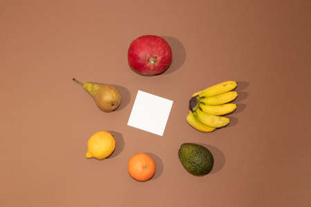 Summer tropical layout made with fresh fruit with white paper on brown background. Minimal flat lay.の写真素材
