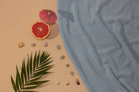 Summer scene with blue beach towel and palm leave and grape with parasol with sea shell. Refreshment concept flat lay.の写真素材