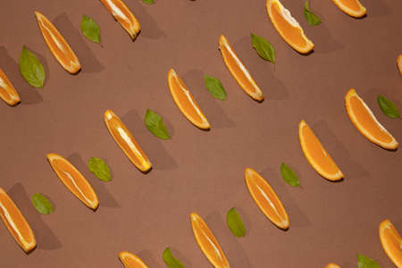 Colorful fruit pattern of fresh orange slices on brown background with leaves top view orange fruit pattern background Flat lay orange background cutの写真素材