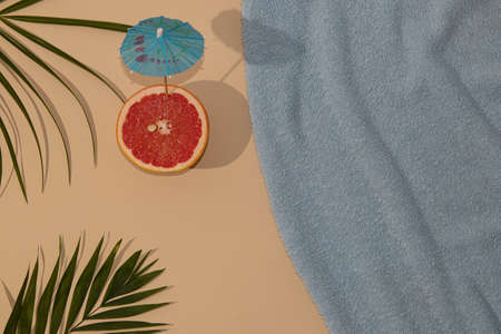 Summer scene with blue beach towel and palm leave and grape with parasol. Minimal concept flat lay.の写真素材