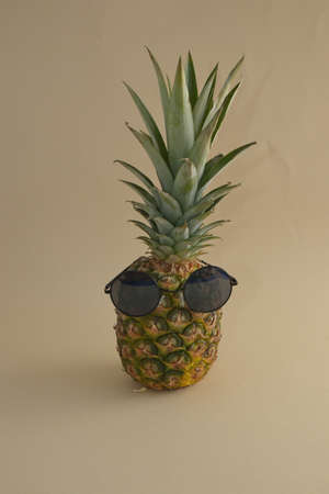 Pineapple, a tropical fruit with sunglasses on a beige background. Minimal concept.の写真素材