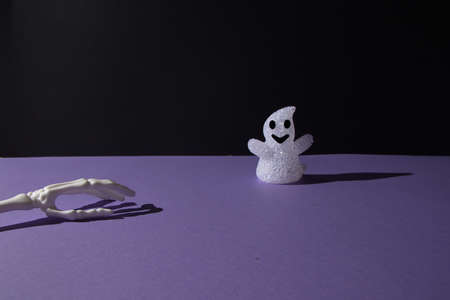 Ghost decoration for Helloween and hand bones on purple black background with copy space. Minimal flat lay concept.の写真素材