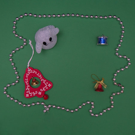Ghost with Christmas decorations and a silver necklace with copy paste on a green background. Flat lay scene.の写真素材
