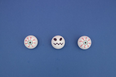 Creepy eyes and between the balls head in a line on a blue background with copy space. Minimal flat lay composition.の写真素材