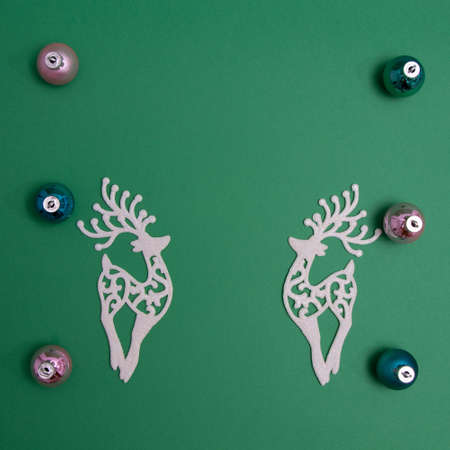 New Year's decorations in various colors with two white reindeer on a green background with copy space. Minimalistic flat lay concept.の写真素材