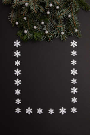 Evergreen branches with snowballs on a black background with copy space framed with snowflakes. Flat lay scene.の写真素材