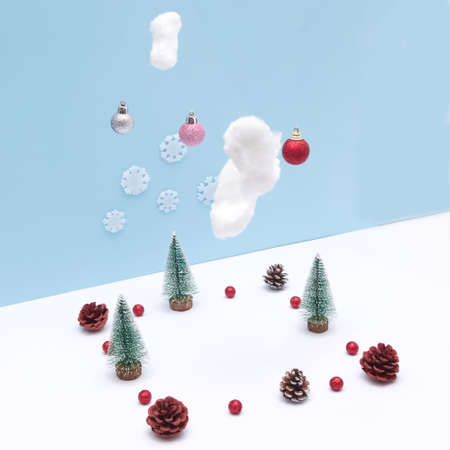 Pine tree in the snow with clouds from which New Year's decorations fall. Copy space in the middle. Minimalistic scene.の写真素材