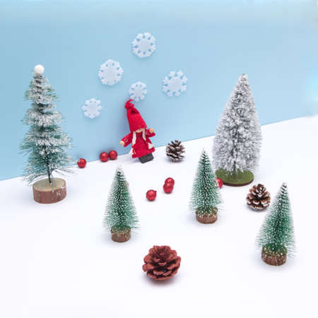 A girl in red in an evergreen forest on the snow with a blue background. Cones scattered on the snow. Minimalistic look.の写真素材