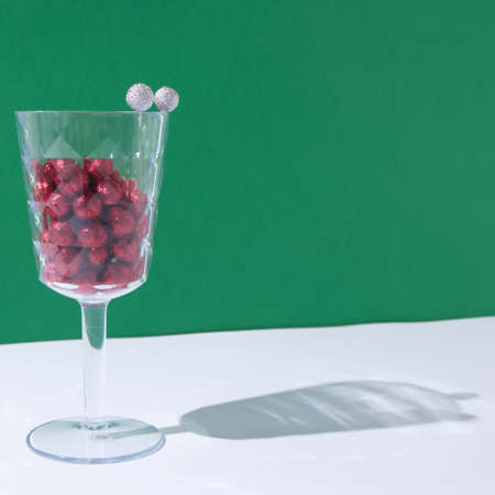 Half full glass with New Year's red balls with a shadow on a white background. New Year's scene.の写真素材