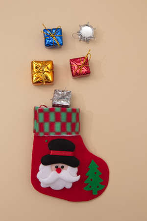 New Year's gifts come out of the red socks of St. Nicholas on a beige background. Flat lay minimal.の写真素材