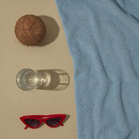 Summer scene with blue beach towel and coconut and red sunglasses and glass. Refreshment concept flat lay.の写真素材