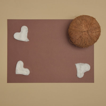 Coconut and coconut flour like heart with dark brown copy space on a beige background. Flat lay concept.の写真素材