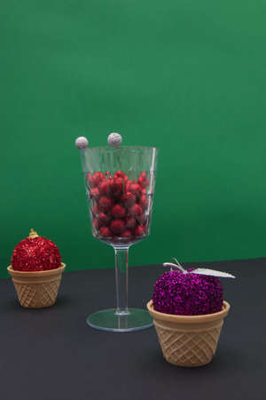 New Year's balls in cones and decoration in a glass on a black green background with copy space. Minimalistic scene.の写真素材