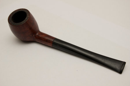 This rustic, artisanal wooden pipe sits atop a stark white surface, inviting a moment of contemplation and reflection for the smoker who appreciates its timeless beauty and the subtle tool of self-expression it providesの写真素材