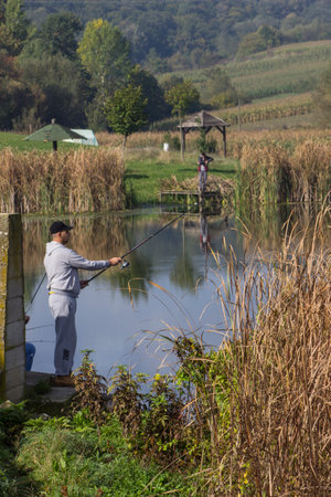 People fishing at a serene lake in nature.の写真素材