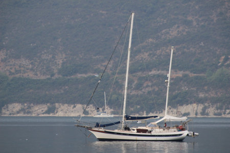 The sun glints off the majestic sailboat as it gracefully skims across the lake, its crisp white sails flapping in the wind and providing a thrilling journey to a destination unknownの写真素材