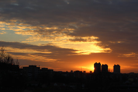 A majestic sunset casts its fiery afterglow across the skyline of the city, creating a surreal backdrop of clouds, skyscrapers, and horizonの写真素材