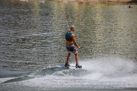 A daring person carving across a lake on a wakeboard, embracing the thrill of a water sport and the beauty of outdoor recreationの写真素材