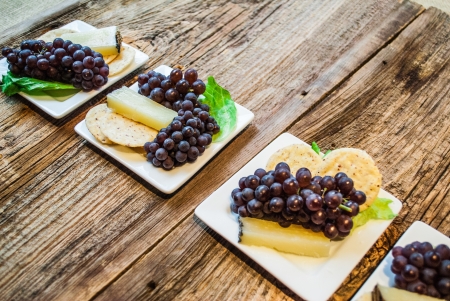 Row of gluten free small plate meals of raw sheeps cheese, rice crackers and organic champagne grapes on a small plateの写真素材