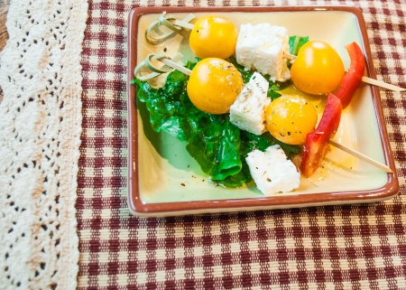 Small appetizer of gluten free yellow organic tomatoes, red peppers, feta cheese, herbs and olive oil as small bite appetizer の写真素材