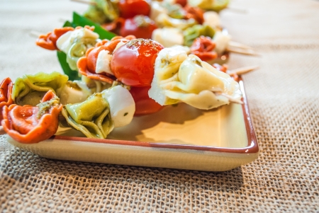 Small appetiser plate of tortellini, tomatoes and mozzarella skewers closeupの写真素材