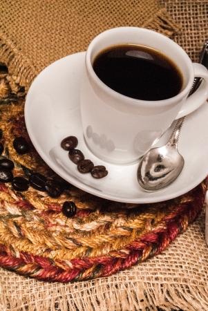 White espresso cup of coffee with a silver spoon against a burlap backgroundの写真素材