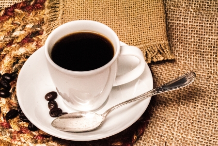 White espresso cup of coffee with a silver spoon against a burlap backgroundの写真素材