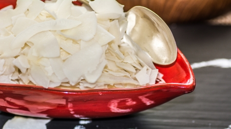 Close up of raw organic coconut chips in a red bowlの写真素材