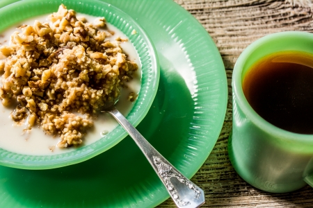 Healthy hot millet porridge in a jadeite bowl with a cup of coffee の写真素材