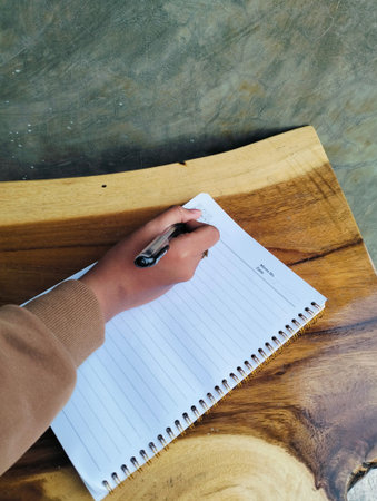 Woman Writing in Notebook on White Wooden Table Top View Workspaceの写真素材