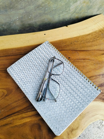 Notebook with pen and glasses on wooden table. professional workspace organization. Top viewの写真素材