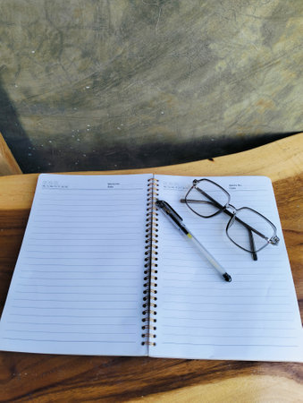 Open notepad with pen and glasses on wooden table. A Blank Sheet Of Notebook With The Items Of A Businessman. Ideal for branding and note-taking app presentations. Close upの写真素材