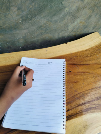 Woman Writing in Notebook on White Wooden Table Top View Workspaceの写真素材