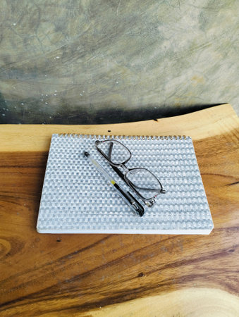 Notebook with pen and glasses on wooden table. professional workspace organization. Top view
