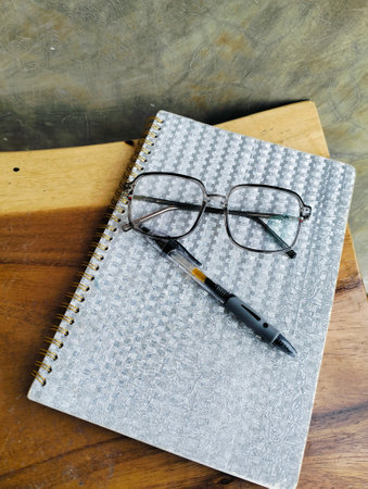 Notebook with pen and glasses on wooden table. professional workspace organization. Top viewの写真素材