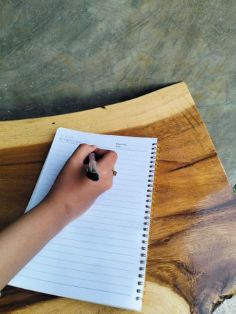 Woman Writing in Notebook on White Wooden Table Top View Workspaceの写真素材