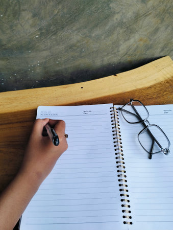 Woman Writing in Notebook on White Wooden Table Top View Workspaceの写真素材