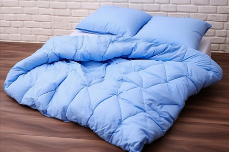 Modern Loft-Style Bedroom Interior with Brick Wall, Blue Pillow, and Bedspread on Light Backgroundの素材