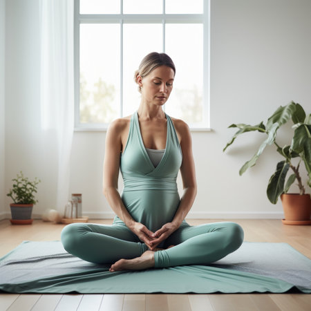 Pregnant woman in mint green yoga clothes meditating and doing yoga on modern home backgroundの素材