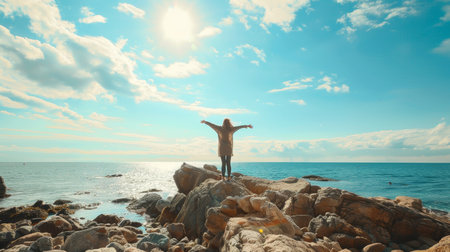 Woman enjoying fresh air and wind on sunny rocky beach, breathing in the serenity of natureの素材
