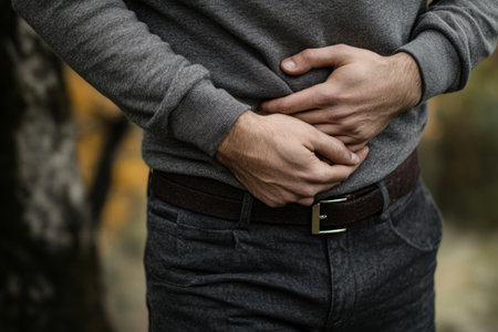 Person grimacing while holding stomach, indicating gastrointestinal distress and health issuesの素材